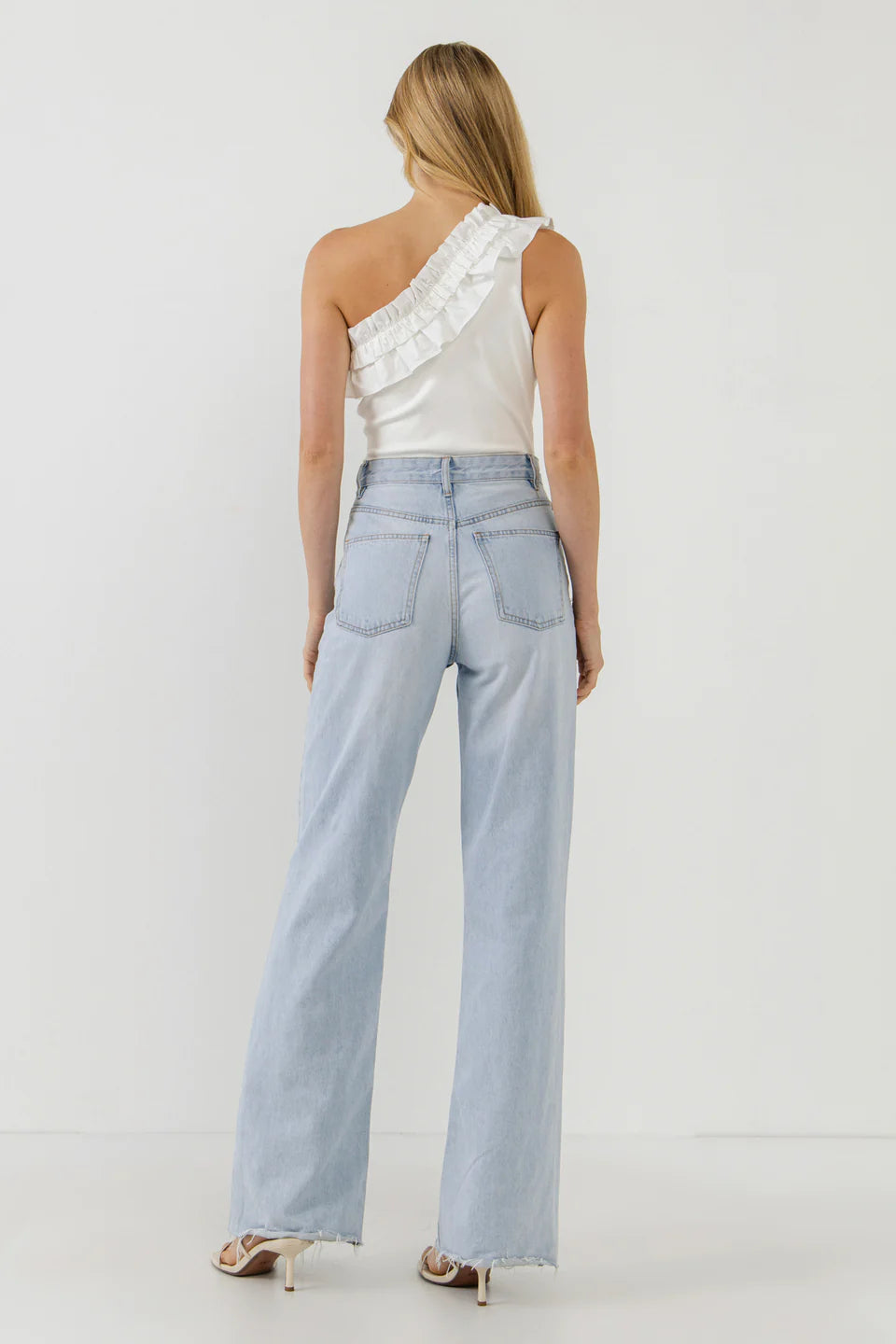 Picture of a blonde model facing away using the Endless Rose White Ruffle Bodysuit and Jeans - CT Grace