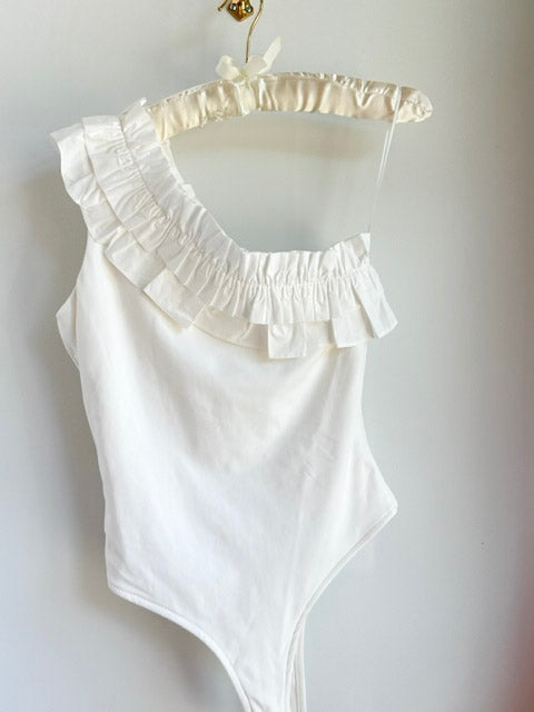 Picture of a white bodysuit hanging from a clothes hanger and a white wall behind it - CT Grace