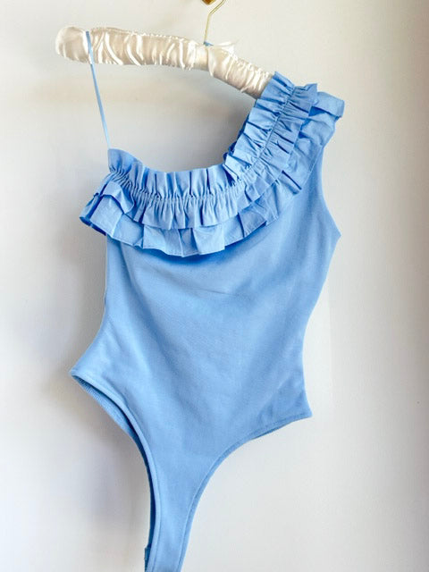 Picture of the Endless Rose Powered Blue Ruffle Bodysuit hanging on a clothes hanger and a white background - CT Grace